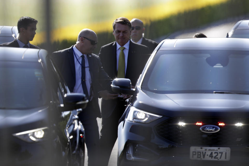 Photographed through a fence, Brazilian President Jair Bolsonaro leaves the presidential residence, Alvorada Palace, in Brasilia, Brazil, Tuesday, March 30, 2021. Amid a slide in his popularity, Bolsonaro has shaken up the Cabinet. (AP Photo/Eraldo Peres)