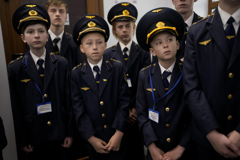 Children in train guard uniforms wait for the departure of a children's train in Kyiv, Ukraine, Saturday, June 4, 2022. The Children's Railways, that lets children drive trains and learn about working in the railways, started to run again Saturday around Syretskyi Park rail track after being closed due to the war with Russia. (AP Photo/Natacha Pisarenko)