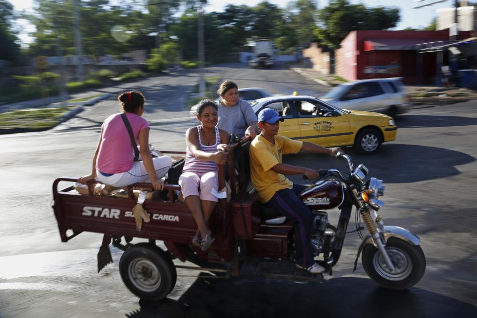 People use a motorcycle along Artigas Avenue in Asuncion, Paraguay, Thursday, Jan. 30, 2014. The city is phasing out horse-draw carts used by people who collect recyclable material and is sending the horses to an equine sanctuary. Horse-cart owners are being offered $350 per each horse as a first installment toward buying three-wheeled moto-carts that can replace the carriages. (AP Photo/Jorge Saenz)