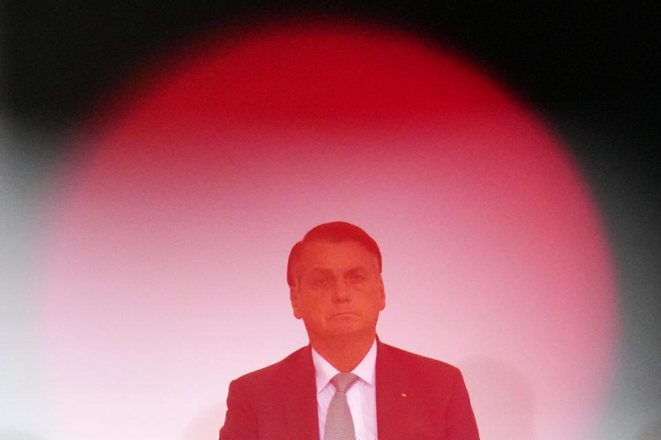 Photographed through the red lightbulb of a videocamera, Brazilian President Jair Bolsonaro attends the launch ceremony for a housing program at Planalto presidential palace in Brasilia, Brazil, Wednesday, Sept. 15, 2021. (AP Photo/Eraldo Peres)