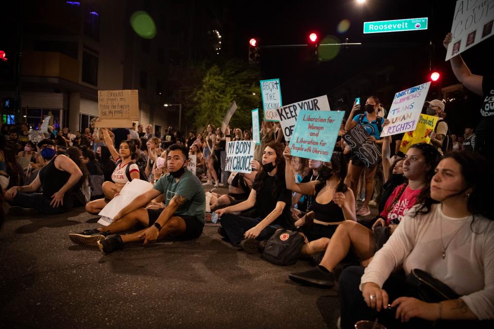The crowd takes a seat in the intersection of Roosevelt Street and Third Street during an abortion rights protest at First Friday in Phoenix.