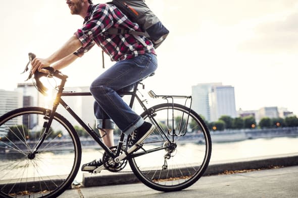 A young man commuting in an urban city environment on his street bicycle, a waterproof bike bag on his back. This is the Eastban