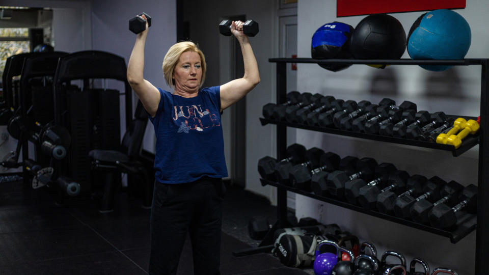 A woman performing a dumbbell shoulder press