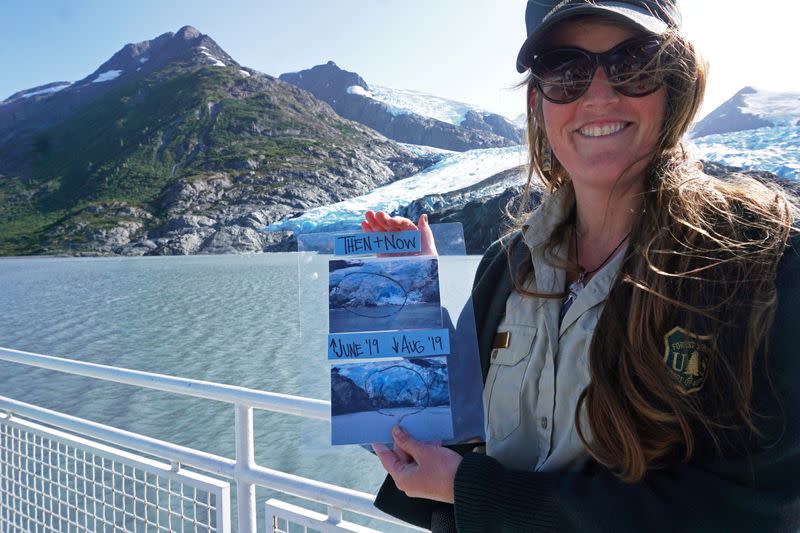 Chugach National Forest ranger Megan Parsley holds photos showing this summer's ice loss at the face of Portage Glacier