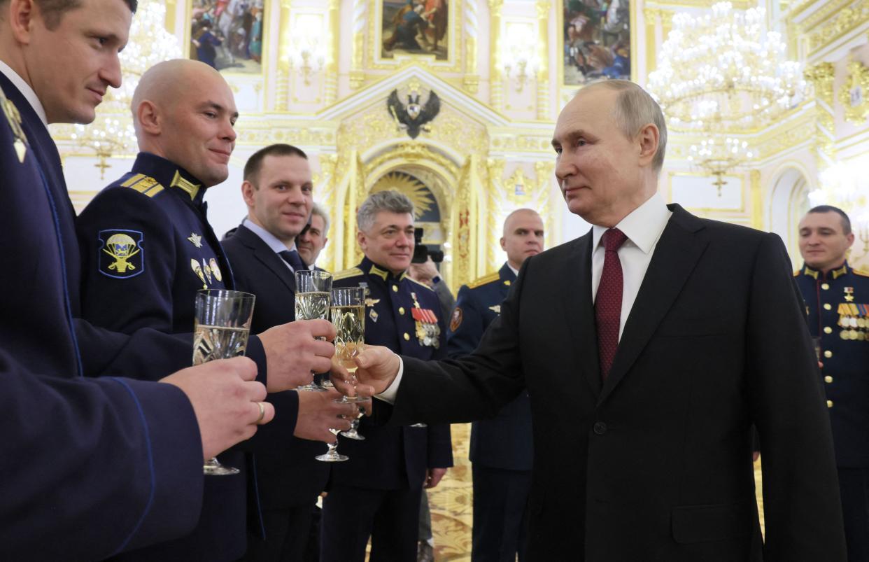 Russian President Vladimir Putin (R) toasts with Russian soldiers after awarding them with the Gold Star medal on the eve of the "Heroes of the Fatherland Day" at the Kremlin in Moscow on December 8, 2022.