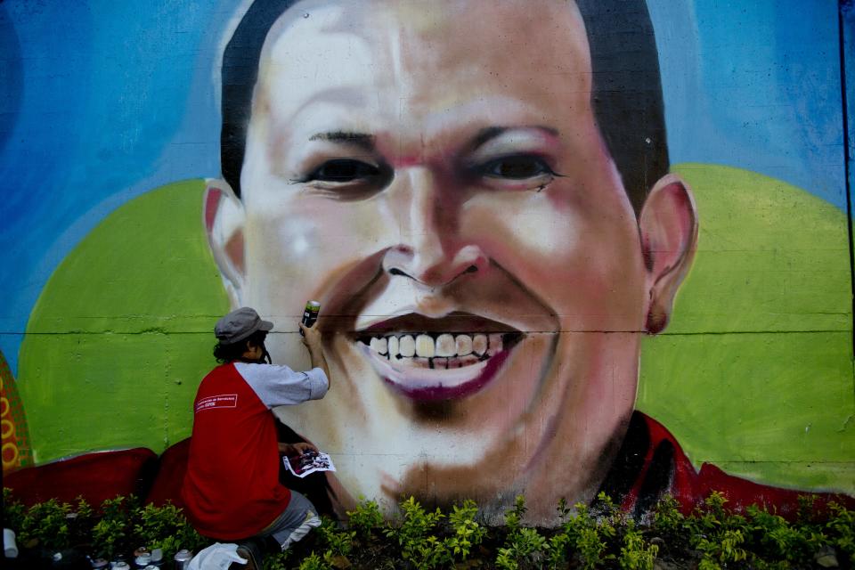 Artist Nicolay Shamanika retouches a mural of Venezuela's former President Hugo Chavez in Caracas, Venezuela, Tuesday, Feb. 25, 2014. (AP Photo/Rodrigo Abd)