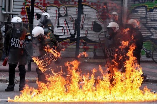 A petrol bomb explodes in front of riot police during protests in Athens on Friday. Greece's ruling coalition was headed for an emergency reshuffle on Friday with the country gripped by a two-day general strike and violent protests in Athens as a chaotic debt default looms closer