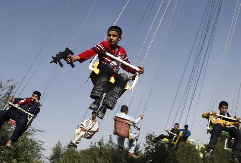 FILE - In this Sunday, Sept. 20, 2009 file photo made by Associated Press photographer Anja Niedringhaus, an Afghan boy holds a toy gun as he enjoys a ride with others on a merry-go-round to celebrate the Eid al-Fitr festival, in Kabul, Afghanistan. Niedringhaus, 48, an internationally acclaimed German photographer, was killed and an AP reporter was wounded on Friday, April 4, 2014 when an Afghan policeman opened fire while they were sitting in their car in eastern Afghanistan. (AP Photo/Anja Niedringhaus, File)