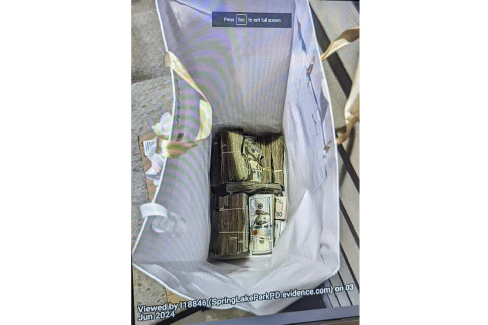 FILE - This photo supplied by the U.S. Attorney's Office for Minnesota shows cash from a bag that was left at the home of a juror in a massive fraud case, June 2, 2024, outside Minneapolis, Minn. Two of five people charged with conspiring to bribe the juror with a bag of $120,000 in cash in exchange for the acquittal of defendants in one of the country’s largest COVID-19-related fraud cases pleaded not guilty Wednesday, July 3, 2024. (U.S. Attorney's Office for Minnesota via AP, File)