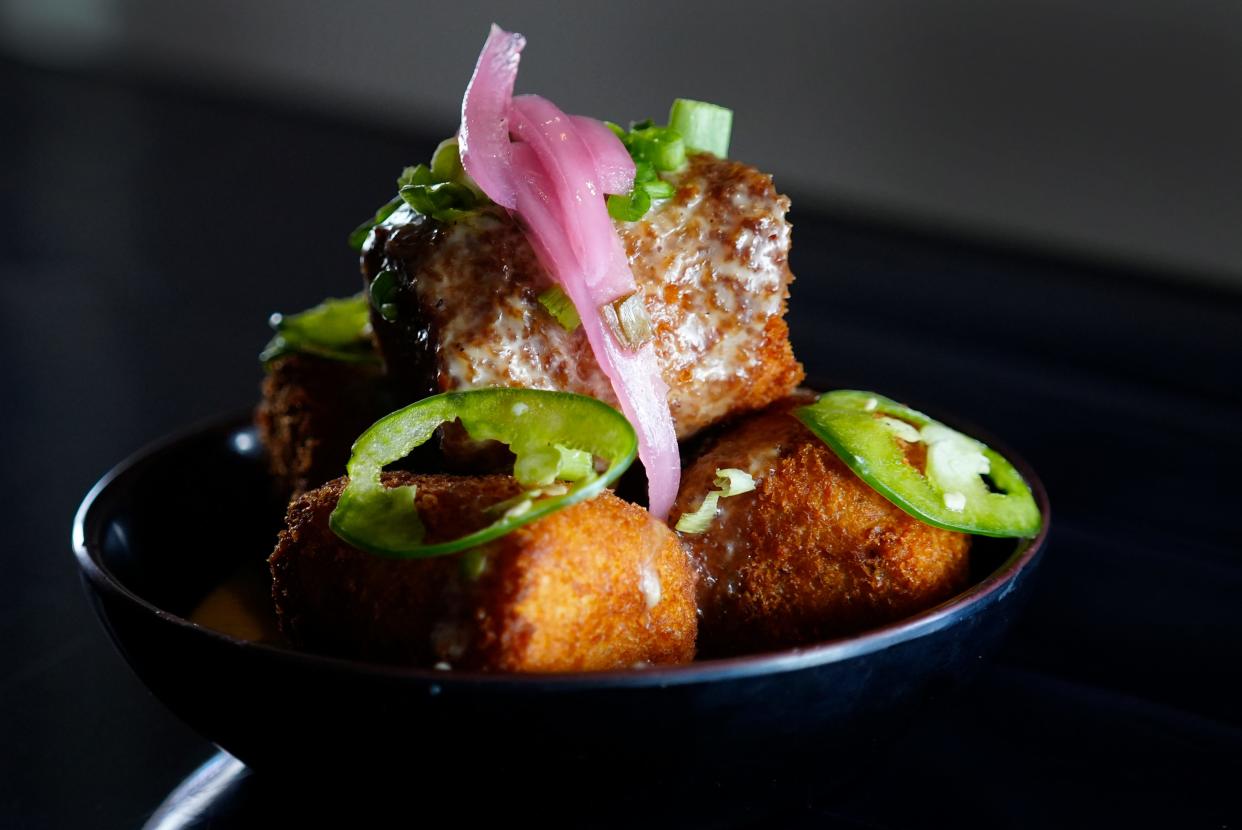 Home Court's oversized tater tots are served with queso, jalapenos, pickled onion and green onion.