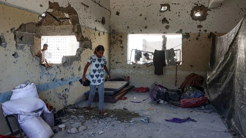 A young Palestinian woman checks the damage inside a classroom at the al-Zahra school used as a refuge by displaced Palestinians, after it was hit by an Israeli strike in the Shujaiya neighbourhood of Gaza City on August 8. - Omar Al-Qattaa/AFP/Getty Images