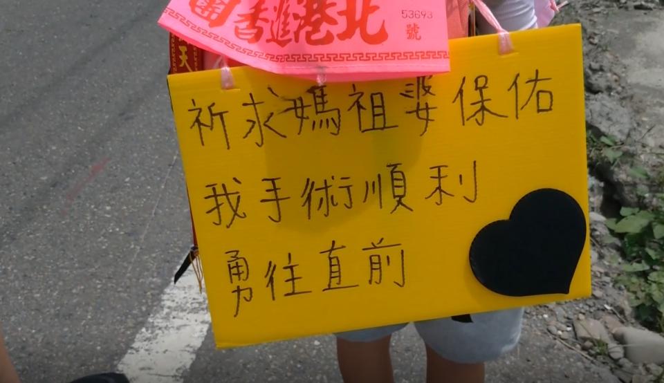 女童身上綁著一塊牌子，上面寫著「祈求媽祖要保佑我手術順利」。（圖／東森新聞）