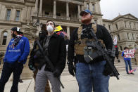 FILE - In this April 15, 2020 file photo, protesters carry guns outside the Capitol Building in Lansing, Mich. A commission that oversees the Michigan Capitol has formed a committee to study whether to ban or restrict guns inside the building. The State Capitol Commission voted Monday, May 11, 2020 to seek input from the Legislature and Gov. Gretchen Whitmer. (AP Photo/Paul Sancya File)