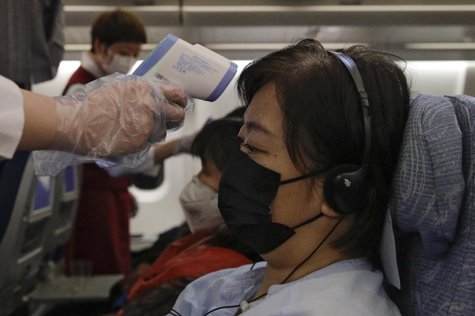 Flight attendants check the temperatures of passengers