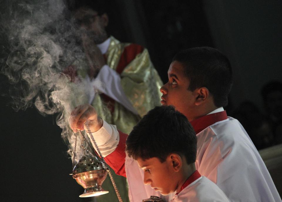 An altar boy holds a censer with burning incense during Christmas mass at a church in Ajmer