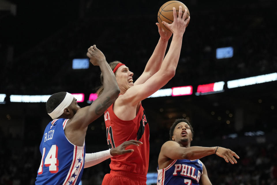 Toronto Raptors forward Kelly Olynyk (41) drives to the basket as Philadelphia 76ers forward Paul Reed (44) and guard Kyle Lowry (7) defend during the first half of an NBA basketball game Sunday, March 31, 2024, in Toronto. (Frank Gunn/The Canadian Press via AP)