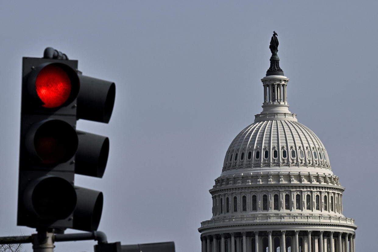 A red light traffic signal is seen with the dome of the U.S. Capitol building in the distance, in Washington, U.S., February 16, 2022. REUTERS/Jon Cherry