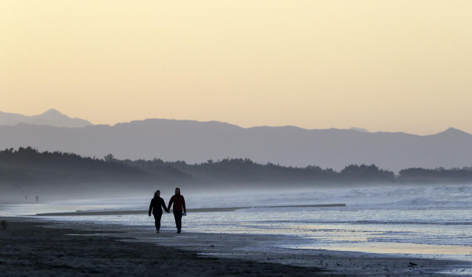 FILE - A couple walk along New Brighton Beach at sunset in Christchurch, New Zealand, Tuesday, June 9, 2020. Whether looking for love or a casual encounter, 3 in 10 U.S. adults say they have used a dating site or app — with mixed experiences, according to a Pew Research Center study. (AP Photo/Mark Baker, File)