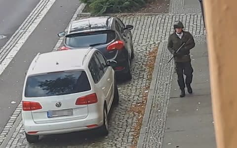 TOPSHOT - In this screenshot taken from a video by ATV-Studio Halle, a man walks with a gun in the streets of Halle an der Saale, eastern Germany, on October 9, 2019. - At least two people were shot dead on a street in Halle, police said, with witnesses saying that a synagogue was among the gunmen's targets as Jews marked the holy day of Yom Kippur. One suspect was captured but with a manhunt ongoing for other perpetrators, security has been tightened in synagogues in other eastern German cities while Halle itself was in lockdown. (Photo by Andreas Splett / ATV-Studio Halle / AFP) / RESTRICTED TO EDITORIAL USE - NO MARKETING - NO ADVERTISING CAMPAIGNS (Photo by ANDREAS SPLETT/ATV-Studio Halle/AFP via Getty Images) - Credit: ANDREAS SPLETT/AFP