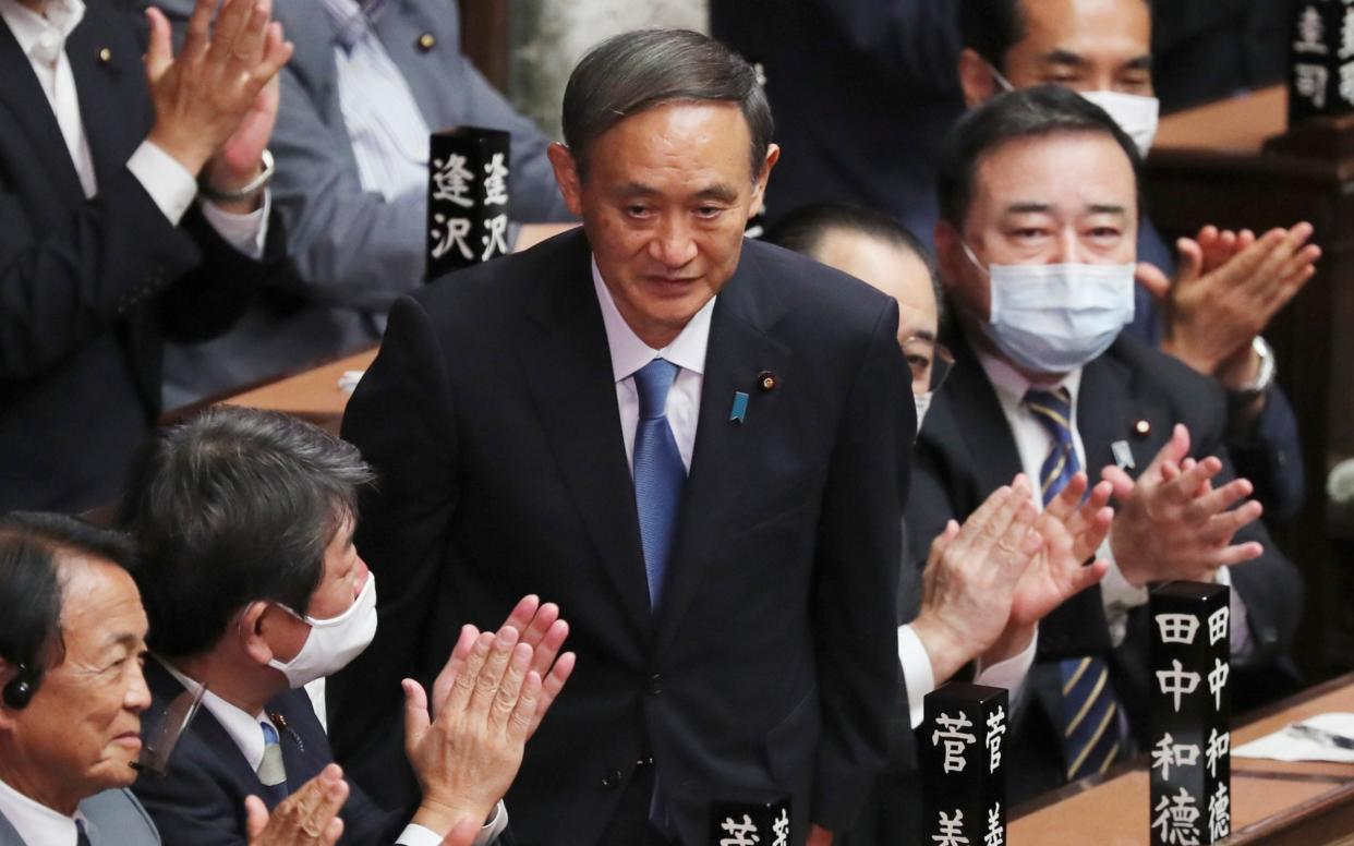 Yoshihide Suga is applauded after being elected as Japan's new prime minister - AP
