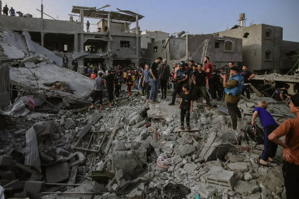 On the 30th day of the conflict between Israel and Palestinian group Hamas, Palestinian civilians and rescue teams sifting through the debris of a collapsed building in Al-Maghazi, located in the central Gaza Strip, in search of survivors and victims following the Israeli bombardment on 5 November 2023 (Middle East Images/AFP via Getty)