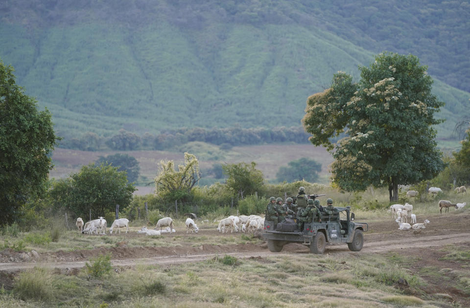 Soldiers patrol near the hamlet Plaza Vieja, in the Michoacan state of Mexico, Thursday, Oct. 28, 2021. The Mexican army has largely stopped fighting drug cartels here, instead ordering soldiers to guard the dividing lines between gang territories so they won’t invade each other’s turf — and turn a blind eye to the cartels’ illegal activities just a few hundred yards away. (AP Photo/Eduardo Verdugo)