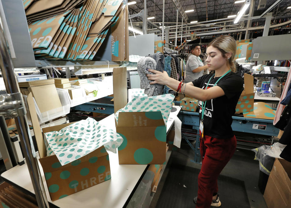 FILE - In this March 12, 2019, file photo, Yakaranday Arce packs sold clothing for shipment at the ThredUp sorting facility in Phoenix. J.C. Penney and Macy’s are in the midst of rolling out a few dozen ThredUp branded shops each in time for the back-to-school shopping season. The partnerships follow a similar deal with department store retailer Stage Stores. (AP Photo/Matt York, File)