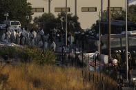 Riot police with buses block the access as their colleagues with special suits to protect against coronavirus, take part in operation to evacuate a road leading from Moria to the capital of Mytilene, where migrants remained camped out on the northeastern island of Lesbos, Greece, Thursday, Sept. 17, 2020. The fires swept through the overcrowded camp at Moria on two nights last week, prompting more than 12,000 migrants and refugees to flee. Most of them remain without shelter even though emergency tents are available at another island site where a new camp is being built. (AP Photo/Petros Giannakouris)