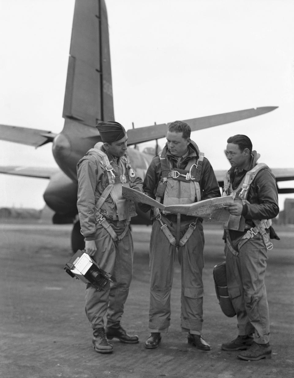 FILE - Associated Press photographer Bede Irvin, left, studies a map of Europe with A-20 bomber pilot Major A.R. Milow, Jr., center, and top-turret gunner S/S Albert Grimsla, right, at an air base in England, May 24, 1944. Associated Press photographer Bede Irvin was killed July 25, 1944 near the Normandy town of St. Lo as he was photographing an Allied bombardment. (AP Photo, File)