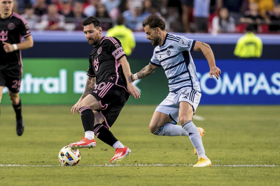 Inter Miami forward Lionel Messi (10) attempts to bypass Sporting Kansas City defender Tim Leibold, right, during the first half of an MLS soccer match Saturday, April 13, 2024, in Kansas City, Mo. (AP Photo/Nick Tre. Smith)