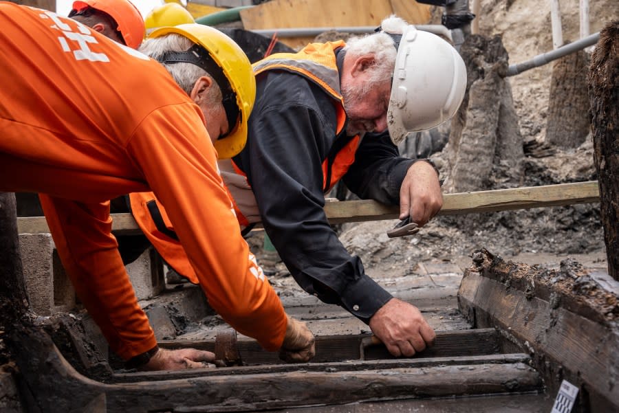 SEARCH archaeologists Dr. Sam Turner (left) and Dr. James Delgado (right) carefully slide a flor (bottom “rib”) from its socket in the centerboard trunk of the ship. Credit: Daniel Fiore (SEARCH, Inc.) & Florida Department of Transportation, District Two.