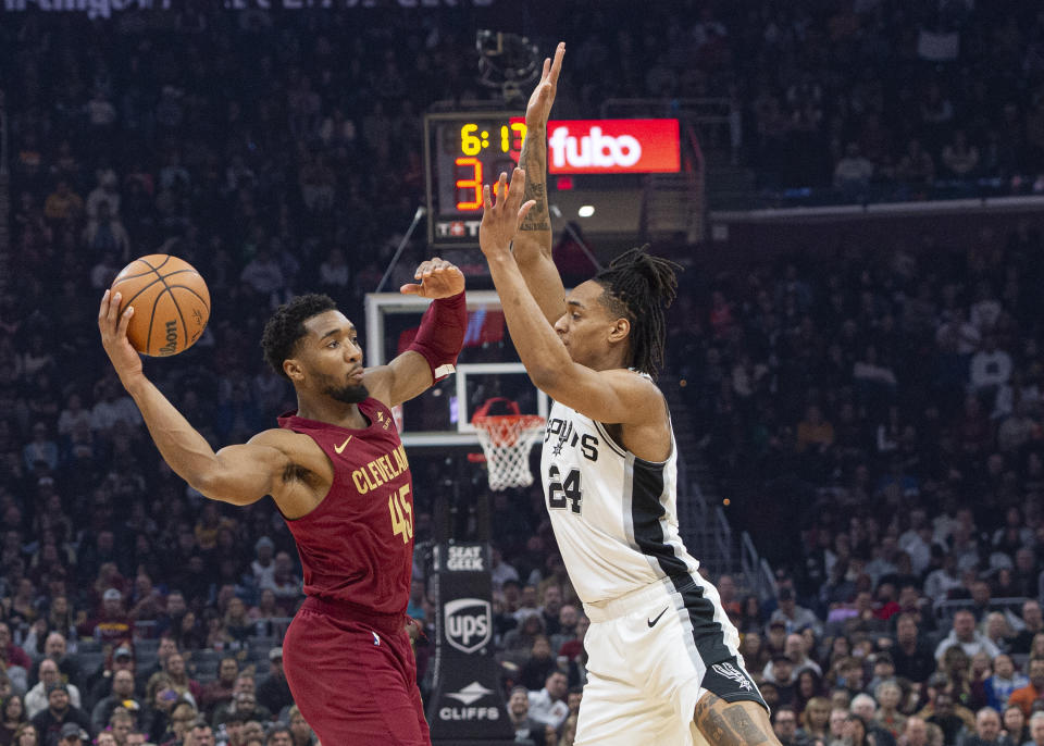 Cleveland Cavaliers' Donovan Mitchell (45) passes the ball past San Antonio Spurs' Devin Vassell (24) during the first half of an NBA basketball game in Cleveland, Sunday, Jan. 7, 2024. (AP Photo/Phil Long)