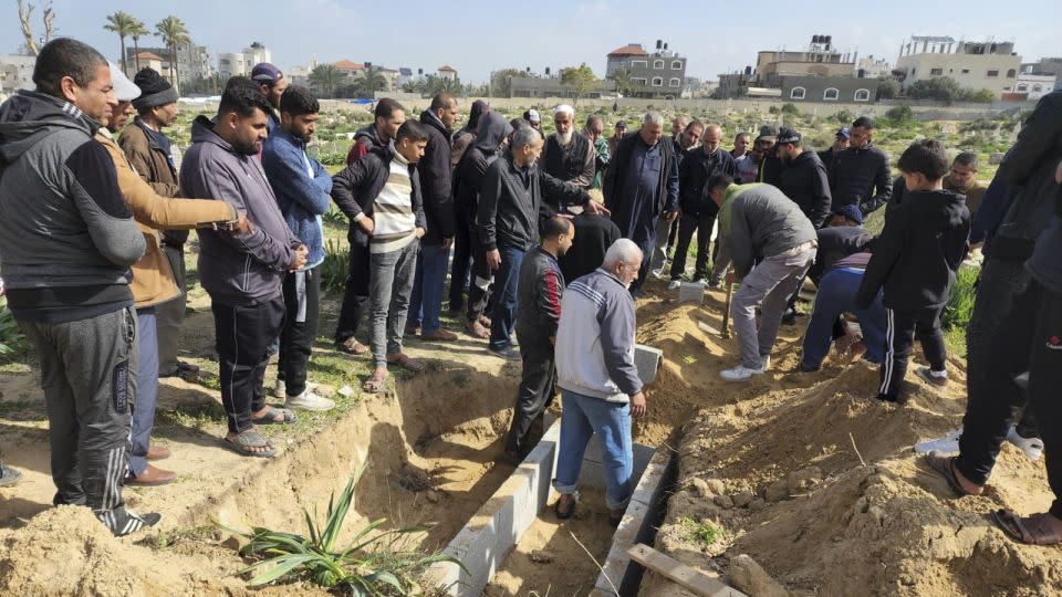 Palestinians gather for the burial of a young girl as Baraka digs her grave. - Mohammad Al Sawalhi/CNN