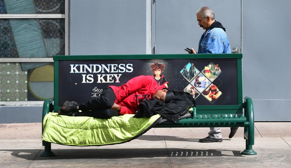 A man sleeps on bench near a bus stop in Los Angeles, California on March 17, 2020. - Cities across the nation are worried about the homeless population as the coronavirus pandemic surges with the US death toll reaching 100. (Photo by Frederic J. BROWN / AFP) (Photo by FREDERIC J. BROWN/AFP via Getty Images)