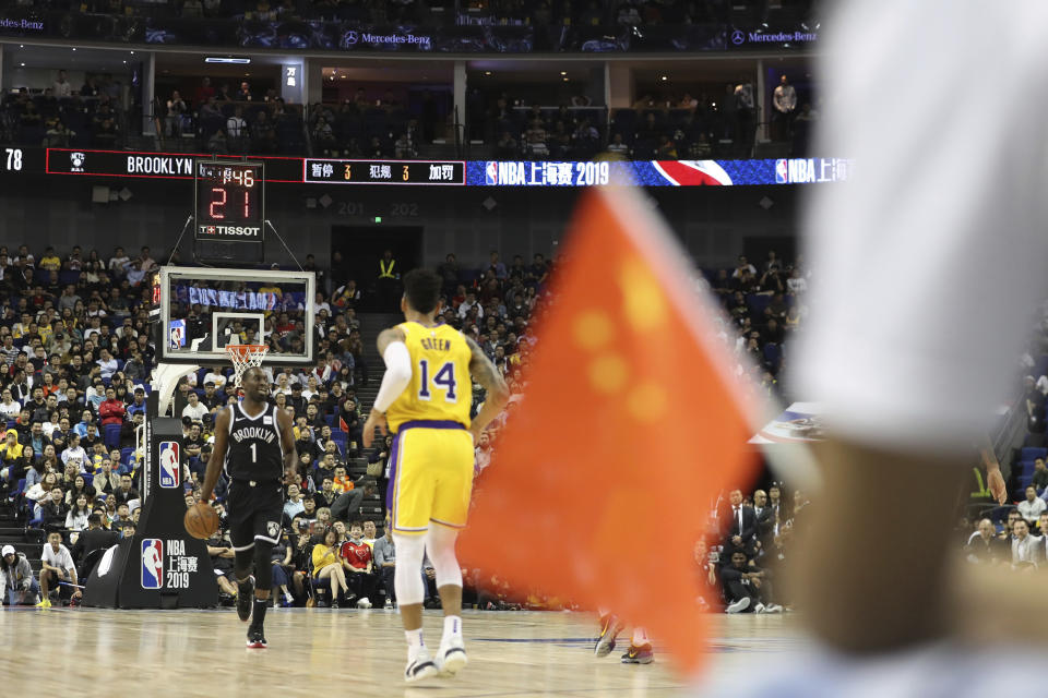 In this Thursday, Oct. 10, 2019, photo, Brooklyn Nets' Theo Pinson, left, drives against Los Angeles Lakers' Danny Green, right, near a Chinese national flag during a preseason NBA game at the Mercedes Benz Arena in Shanghai, China. When Houston Rocket's general manager Daryl Morey tweeted last week in support of anti-government protests in Hong Kong, everything changed for NBA fans in China. A new chant flooded Chinese sports forums: "I can live without basketball, but I can't live without my motherland." (AP Photo, File)