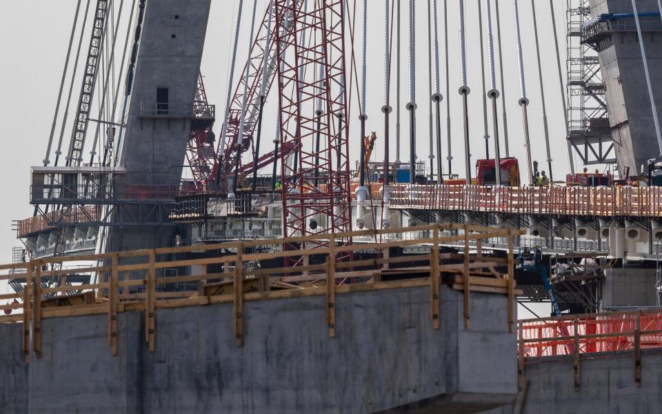 Construction workers stand on the Gordie Howe International Bridge in Detroit on Tuesday, Aug. 8, 2023. Crews are also installing anchor boxes along the towers, which secure the cables to the towers. The bridge needs 216 cables, 108 cables on each tower, to maintain stability and hold the entire structure to the tower through tension.