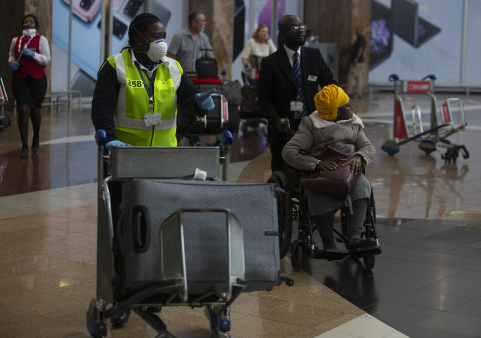 An elderly passenger arrives in a wheelchair at Johannesburg's O.R. Tambo International Airport, Monday, March 16, 2020, a day after President Cyril Ramaphosa declared a national state of disaster. Ramaphosa said all schools will be closed for 30 days from Wednesday and he banned all public gatherings of more than 100 people. South Africa will close 35 of its 53 land borders and will intensify screening at its international airports. For most people, the new COVID-19 coronavirus causes only mild or moderate symptoms. For some it can cause more severe illness. (AP Photo/Denis Farrell)