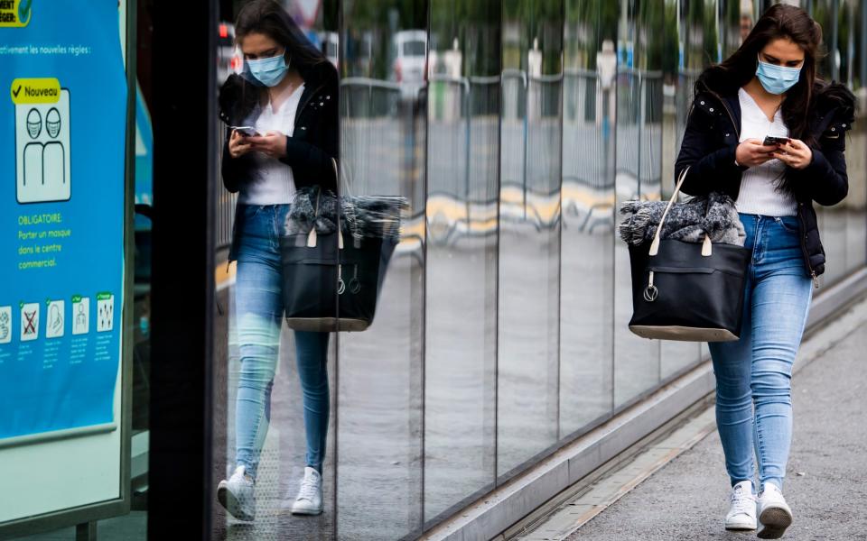 A woman wearing a protective mask in Fribourg, Switzerland, - Jean-Christophe Bott/Keystone via AP