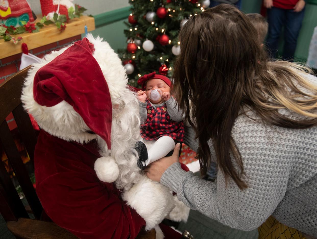 Nellie Howard is handed her daughter, Novah Scales, 2 months, after her first sitting with Santa at Freedom Town Hall in Freedom Township.