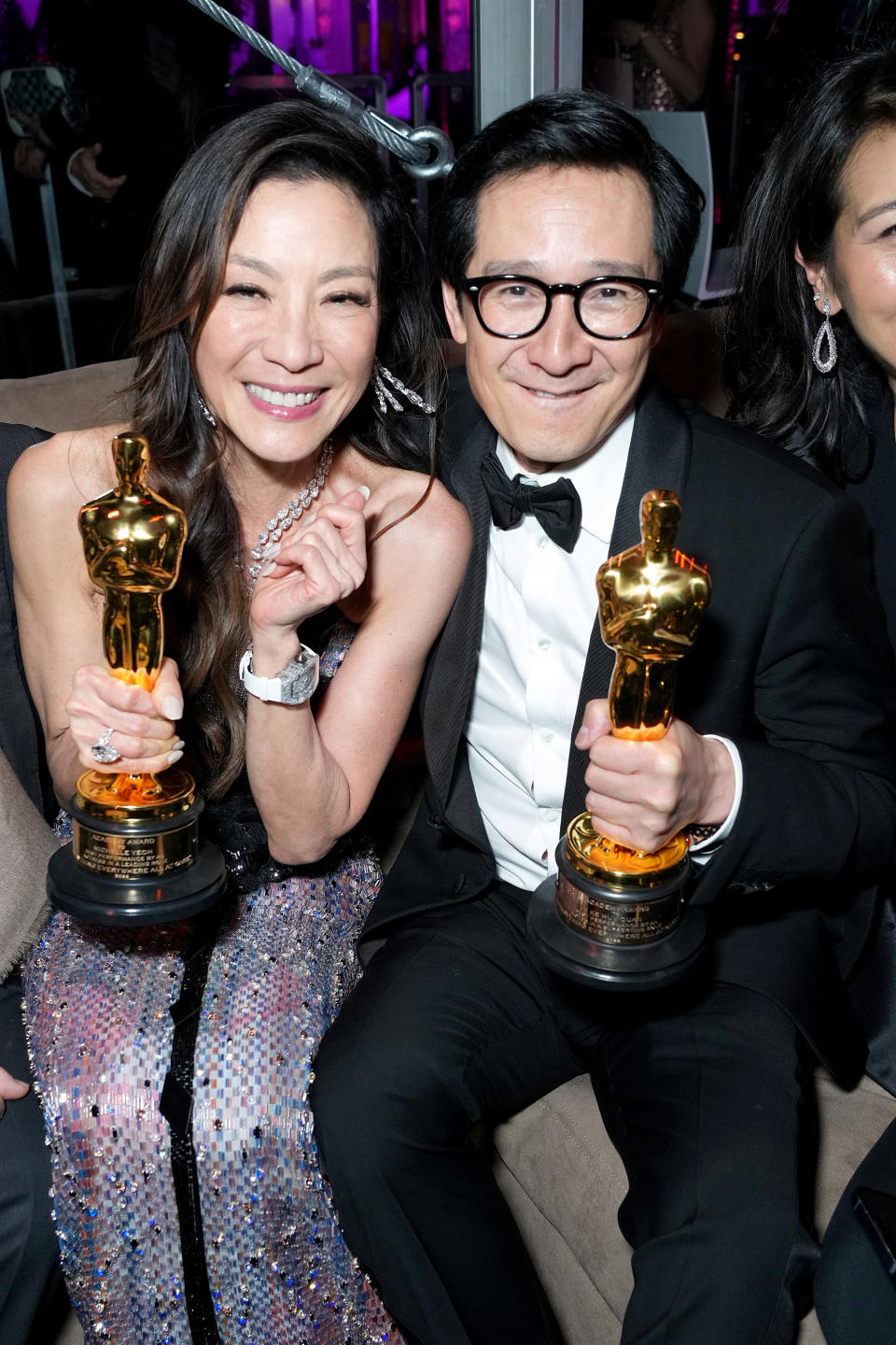 Michelle Yeoh and Ke Huy Quan sitting next to each other holding their Oscar Awards