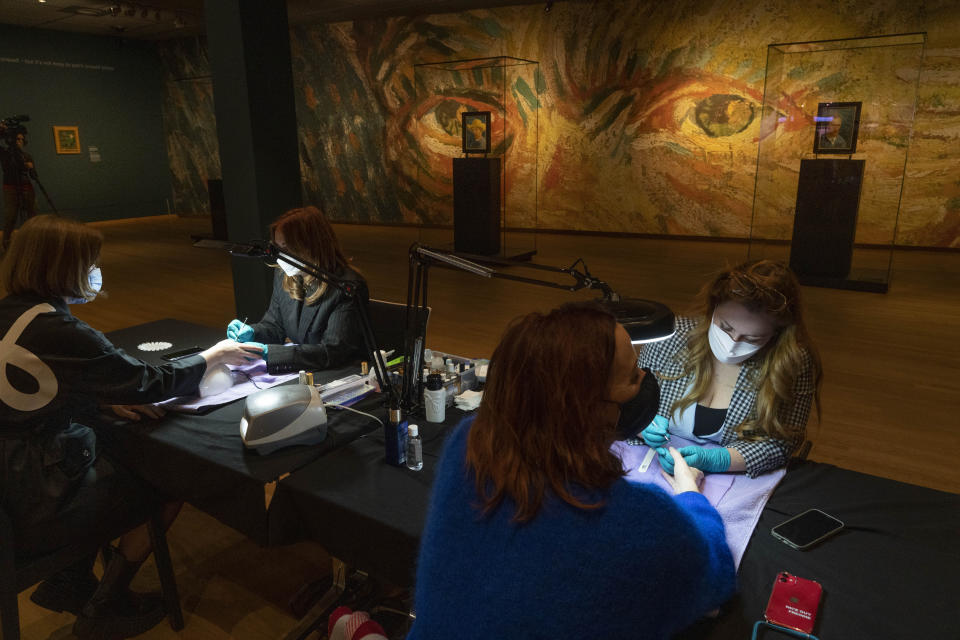 Two women get a manicure at the Van Gogh museum in Amsterdam, Wednesday, Jan. 19, 2022, as Dutch museums, theaters and concert halls played host Wednesday to businesses that are allowed to open to customers as a protest against their own continuing lockdown closures. (AP Photo/Peter Dejong)