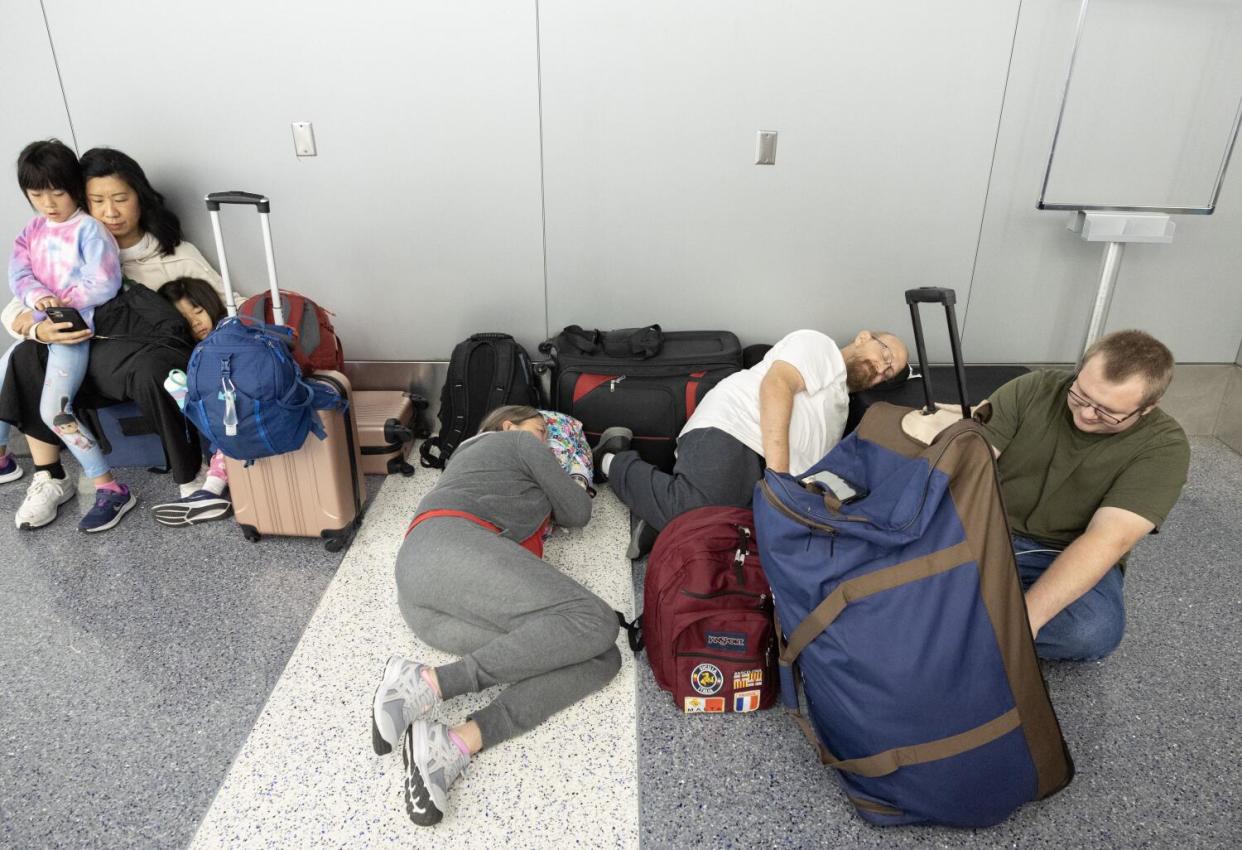 A family rests on the floor at the United Airlines terminal after their flight to Sydney, Australia was canceled Thursday.