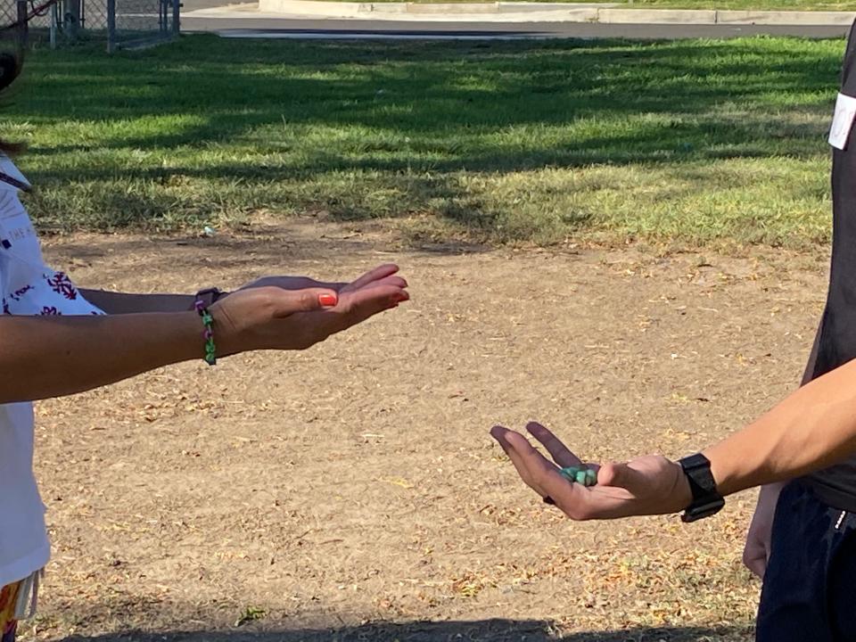 My aunt and brother holding out their hands while playing the marble game.