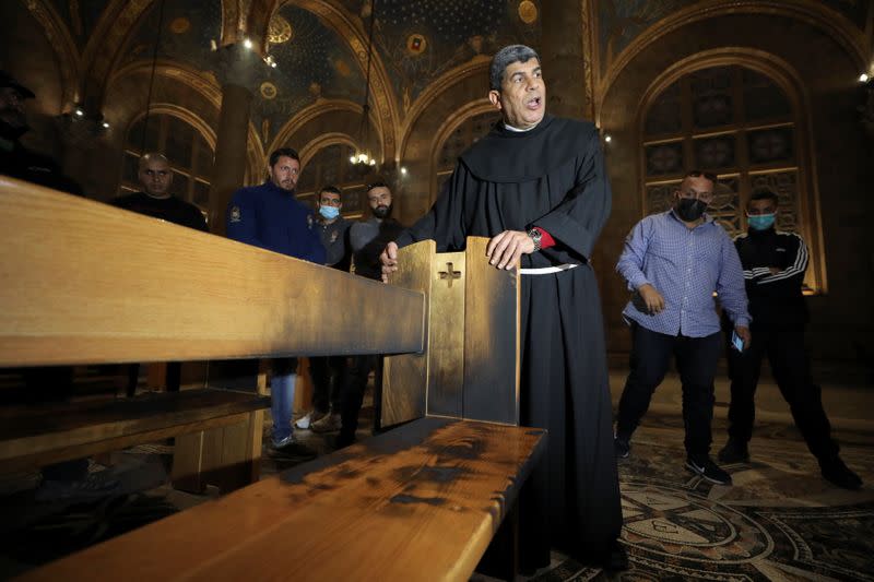 A priest inspects a damaged church bench after a man tried to set fire to the Church of All Nations next to the Garden of Gethsemane in Jerusalem