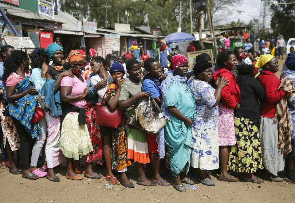 Women queue for a planned distribution of food for those suffering under Kenya's coronavirus-related movement restrictions, before the crowd pushed through a gate and created a stampede, causing police to fire tear gas and leaving several injured, at a district office in the Kibera slum, or informal settlement, of Nairobi, Kenya, Friday, April 10, 2020. (AP Photo/Brian Inganga)