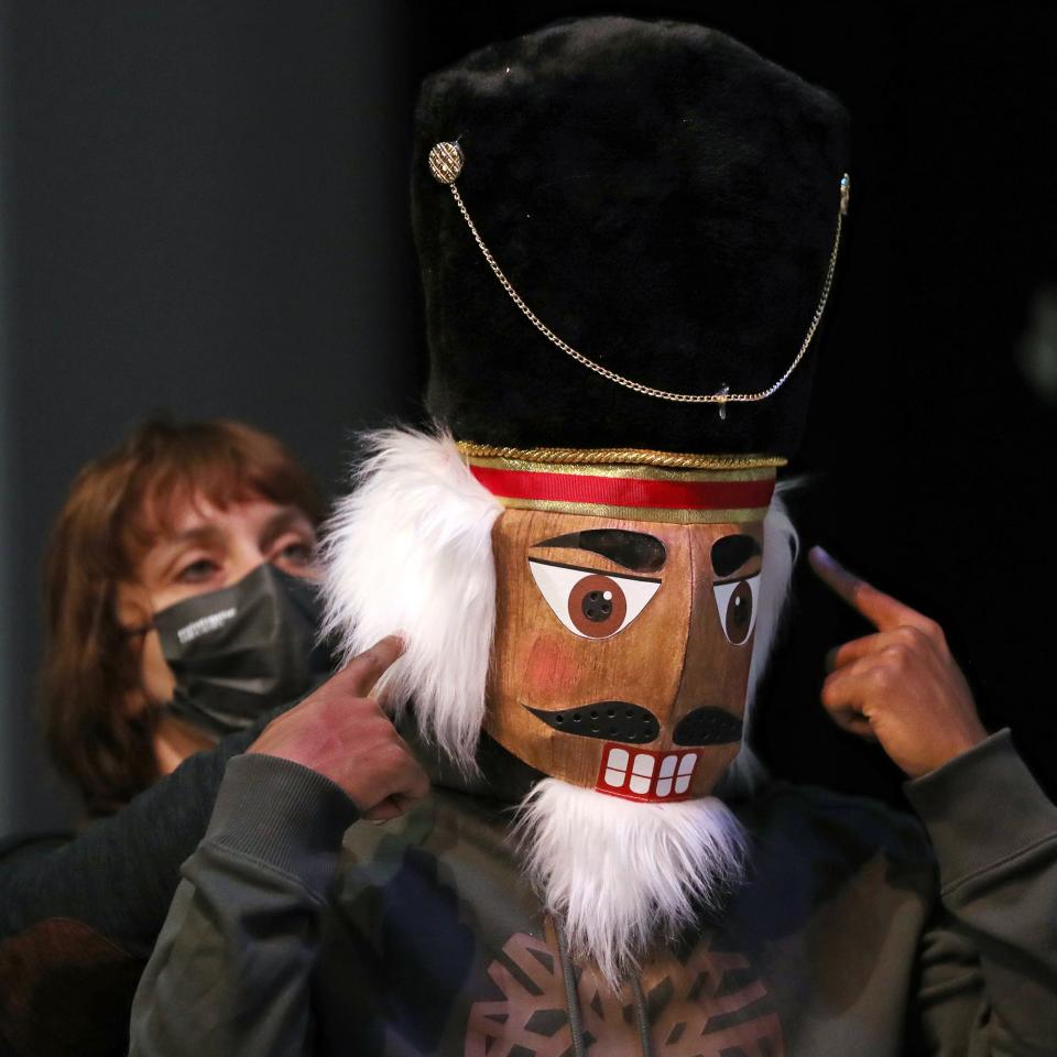 Sikhumbuzo Hlahleni gets help putting on his Nutcracker mask during rehearsal for "The Akron Nutcracker" on Sunday at Guzzetta Hall.