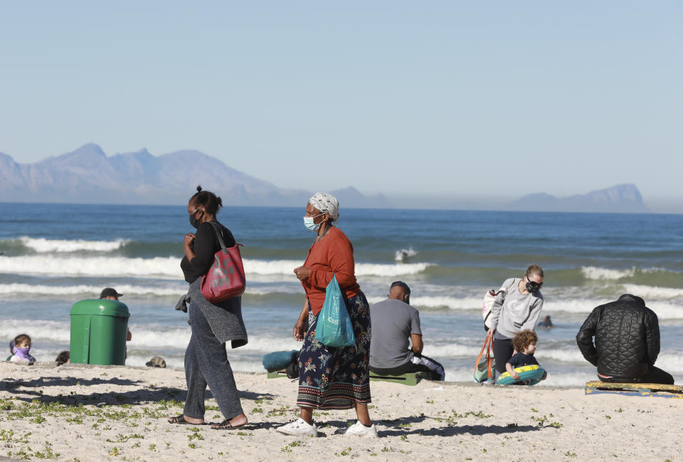 Women walk on the beach at Muizenberg, Cape Town, South Africa, Tuesday June 16, 2020. The country now has more than a quarter of the coronavirus cases on the 54-nation African continent with more than 73,000 cases after new, record-high infections were registered in South Africa over the weekend. (AP Photo/Nardus Engelbrecht)