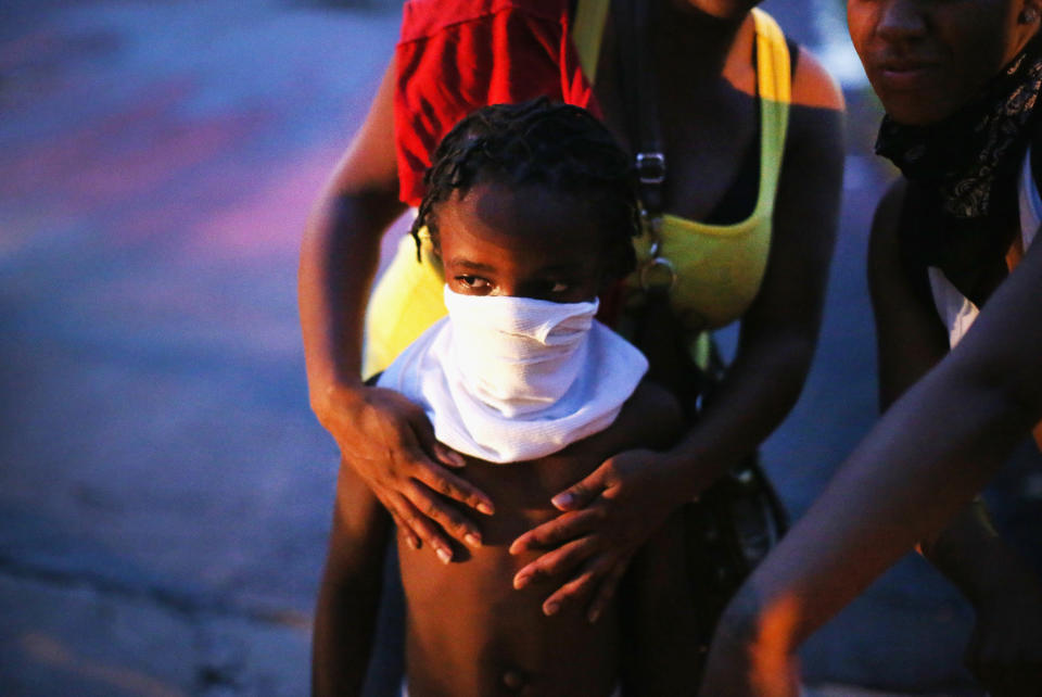 FERGUSON, MO - AUGUST 11:  A child uses a rag to shield his face from tear gas being fired by police who used it to force protestors from the business district into nearby neighborhoods on August 11, 2014 in Ferguson, Missouri. Police responded with tear gas and rubber bullets as residents and their supporters protested the shooting by police of an unarmed black teenager named Michael Brown who was killed Saturday in this suburban St. Louis community. Yesterday 32 arrests were made after protests turned into rioting and looting in Ferguson.  (Photo by Scott Olson/Getty Images)