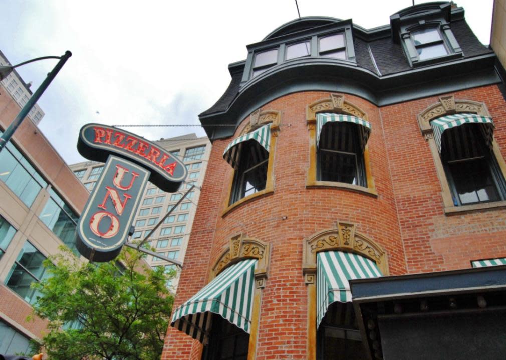 A historic brick ornate building with green and white striped awnings and a Pizzeria Uno sign.