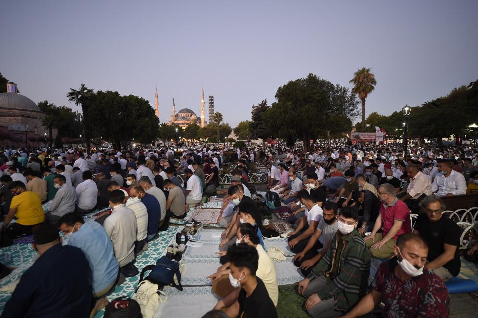 Muslims, wearing protective masks as a precaution against the coronavirus, offer their prayers during the Eid al-Adha prayer backdropped by the Byzantine-era Hagia Sophia, recently converted back to a mosque, in the historic Sultanahmet district of Istanbul, early Friday, July 31, 2020. (AP Photo/Yasin Akgul)